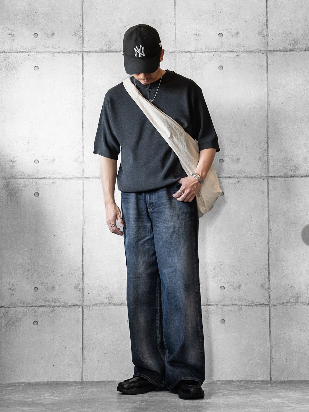 グレー系のニット/セーター、ブルー系のデニムパンツ、ホワイト系のショルダーバッグを着用したメンズの春コーディネートの1枚目の写真