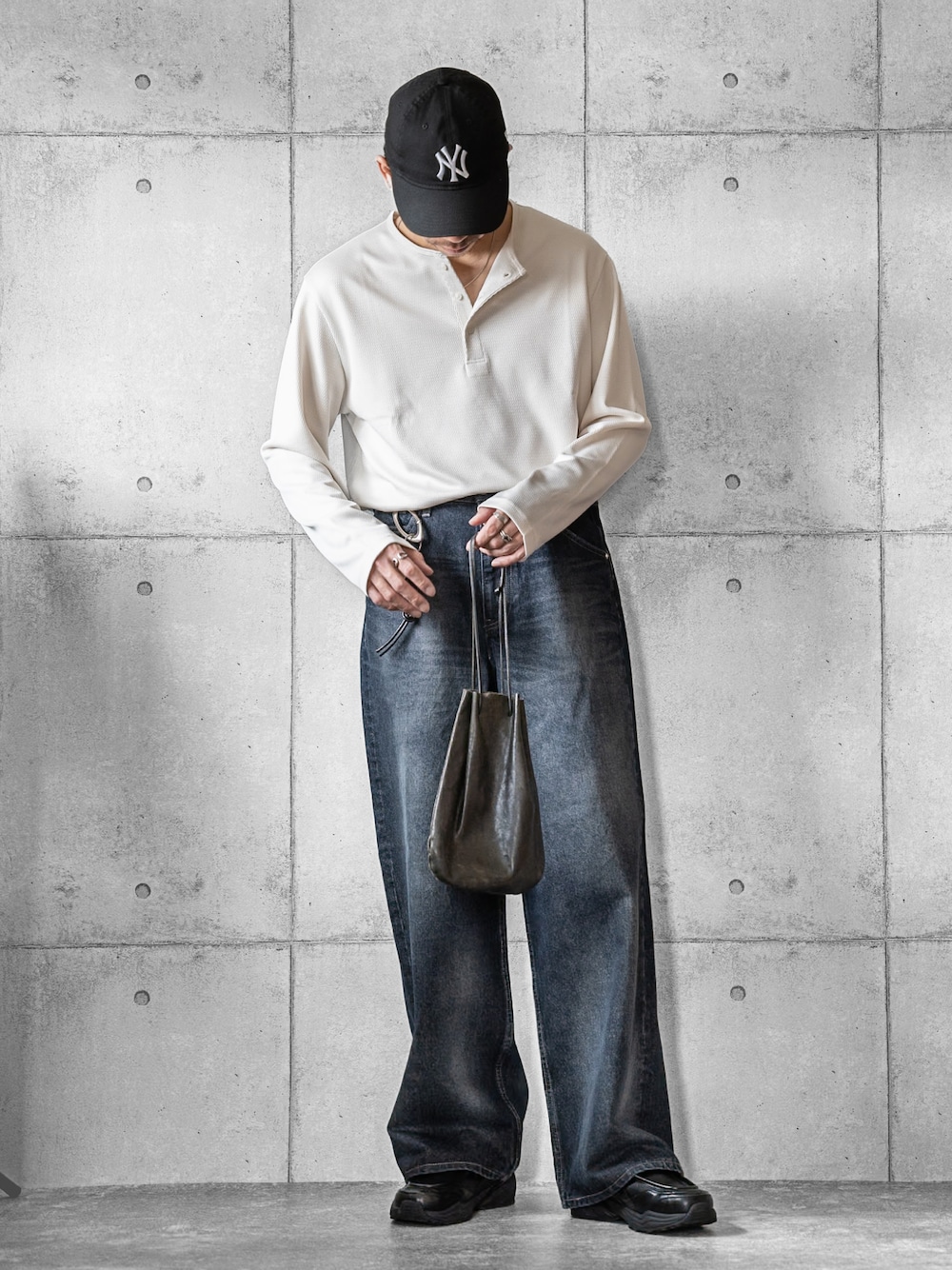 ブラック系のショルダーバッグ、ホワイト系のTシャツ/カットソー、ブルー系のデニムパンツを着用したメンズの春コーディネートの1枚目の写真