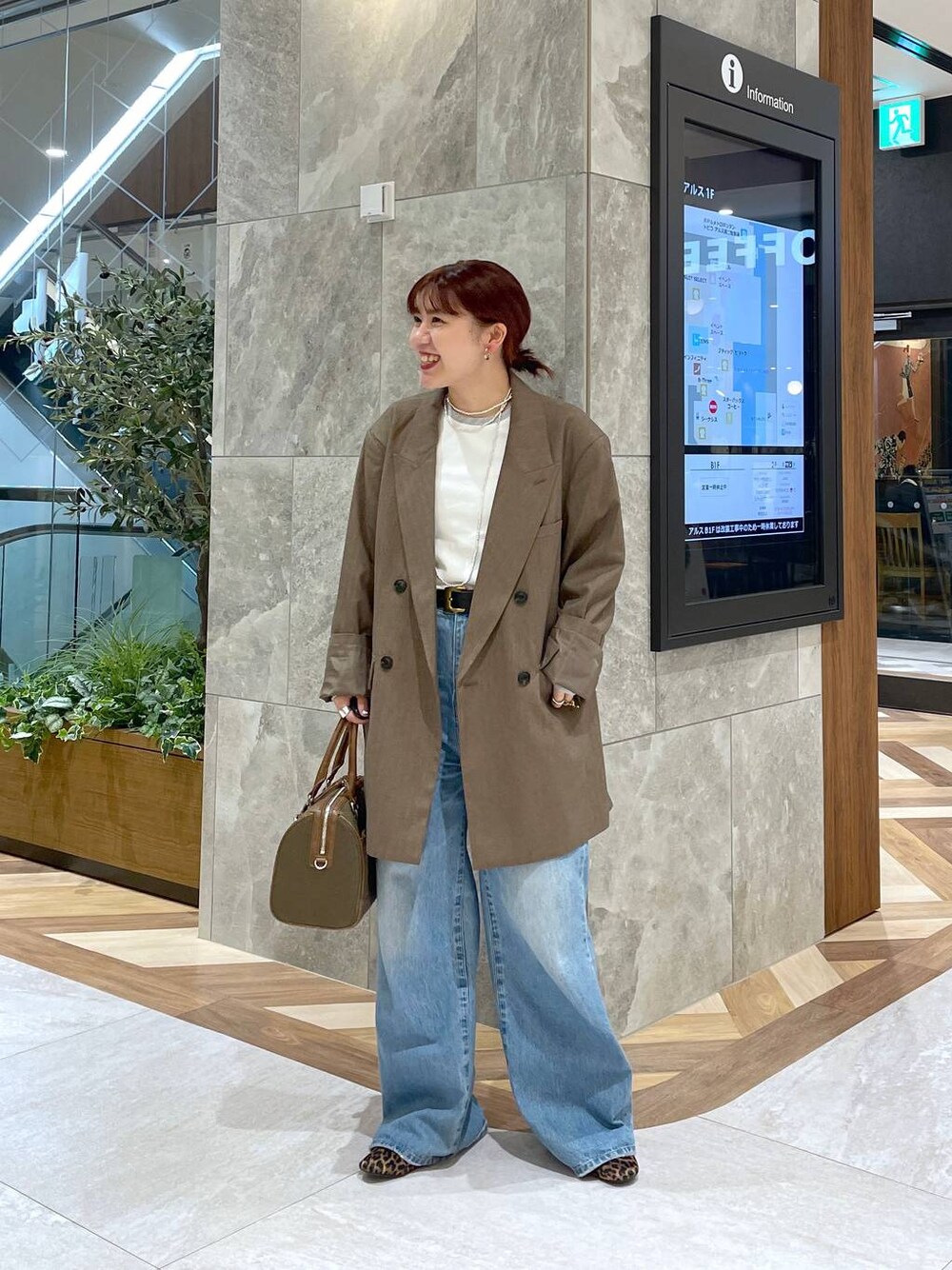 ブルー系のデニムパンツ、グリーン系のボストンバッグ、ブラウン系のテーラードジャケットを着用したレディースの秋コーディネートの1枚目の写真