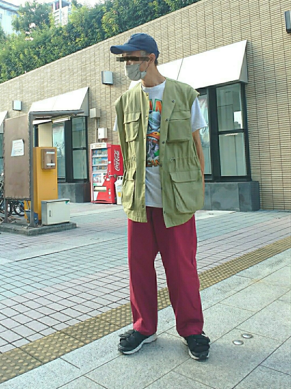 グリーン系のベスト、レッド系のパンツ、ブラック系のサンダルを着用したメンズの夏コーディネートの1枚目の写真