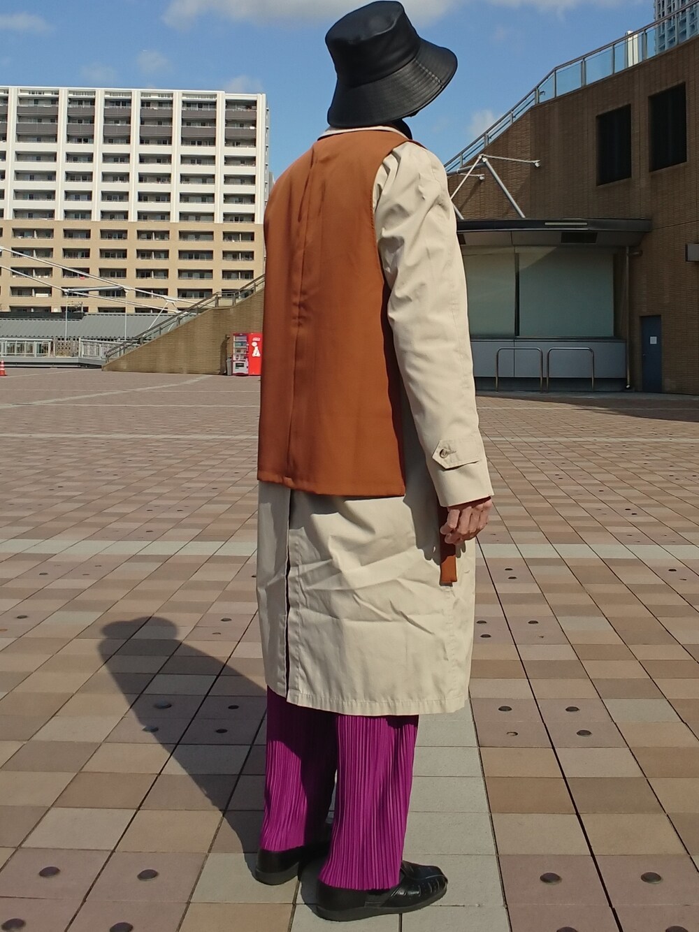 ブラウン系のベスト、ブラック系のニット/セーター、ベージュ系のステンカラーコートを着用したメンズの冬コーディネートの2枚目の写真