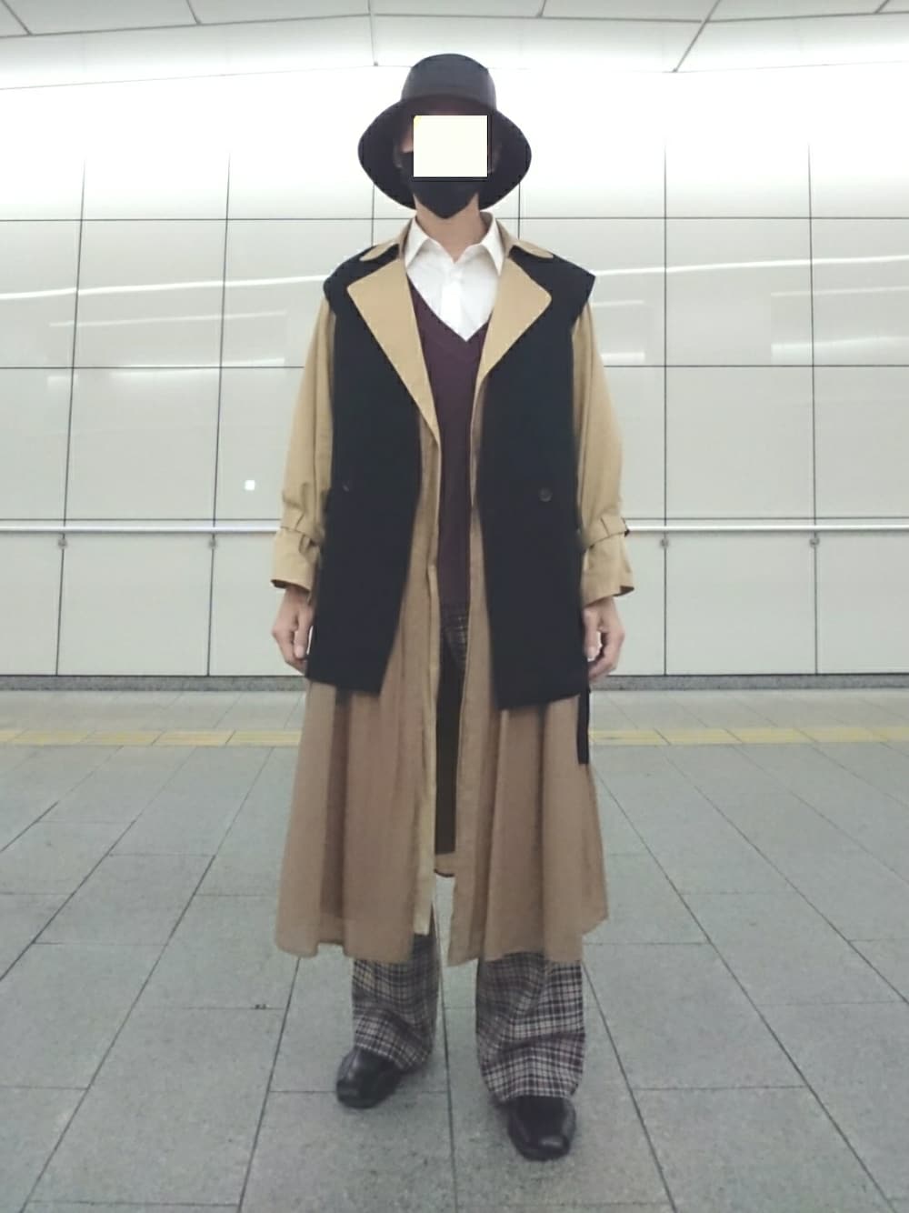 ブラウン系のベスト、ブラック系のベスト、ブラウン系のトレンチコートを着用したメンズの秋コーディネートの1枚目の写真