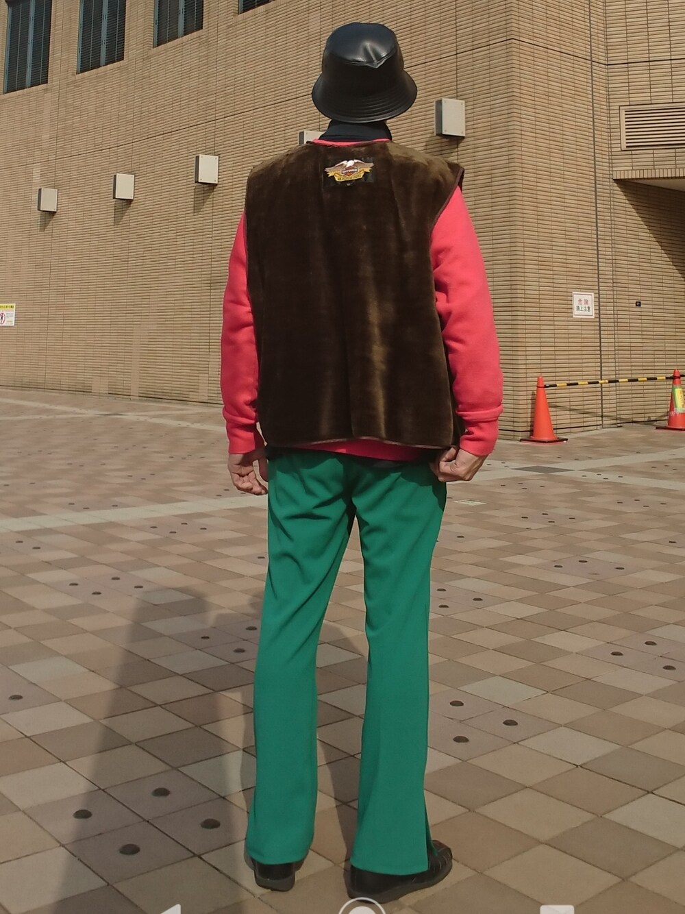 レッド系のスウェット、ブラウン系のベスト、グリーン系のスラックスを着用したメンズの春コーディネートの2枚目の写真