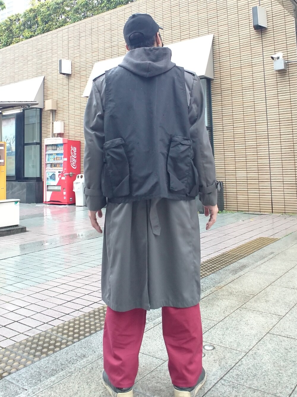 ブラック系のパーカー、グレー系のトレンチコート、ブラック系のベストを着用したメンズの春コーディネートの2枚目の写真