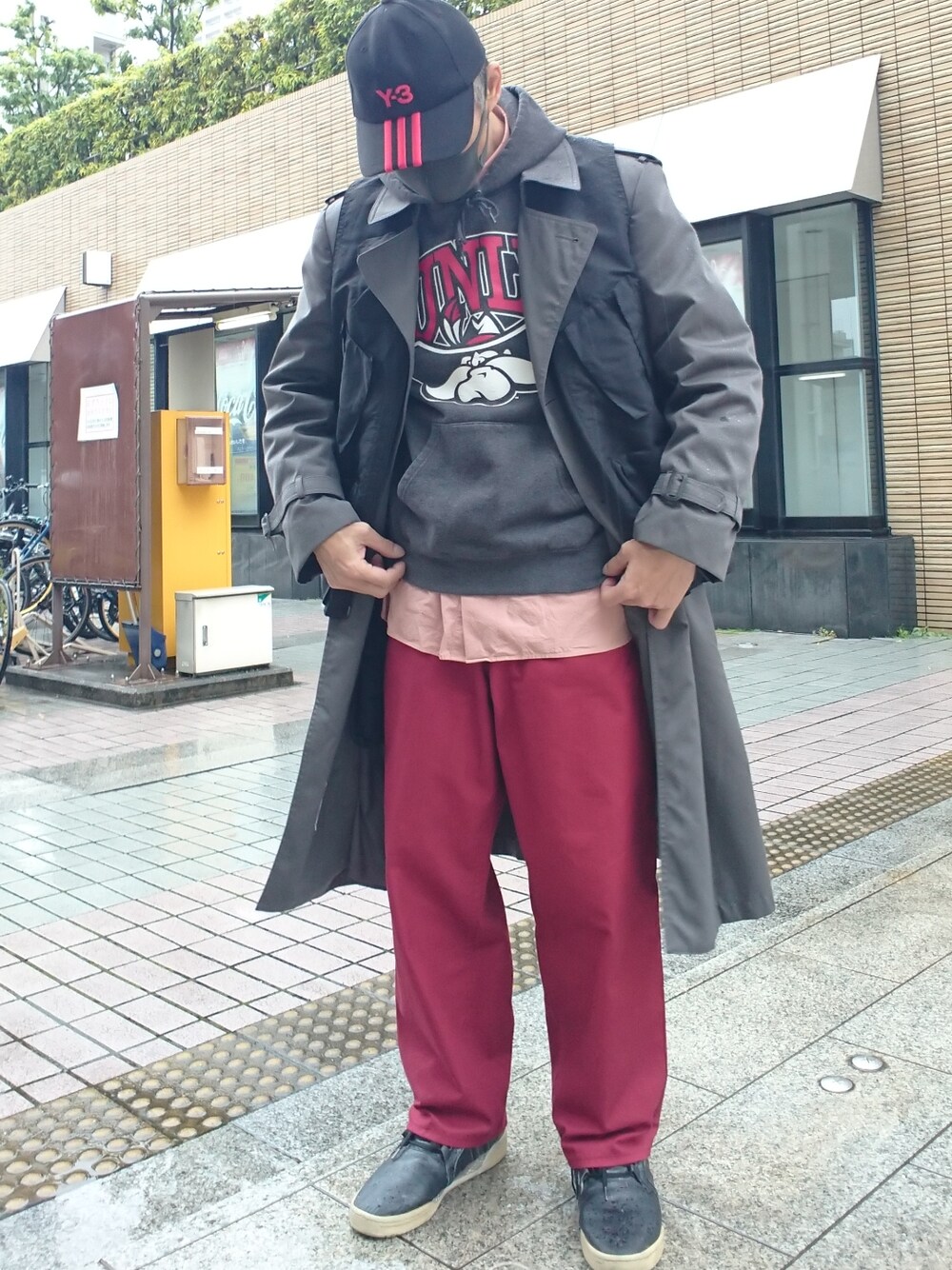 ブラック系のパーカー、グレー系のトレンチコート、ブラック系のベストを着用したメンズの春コーディネートの1枚目の写真