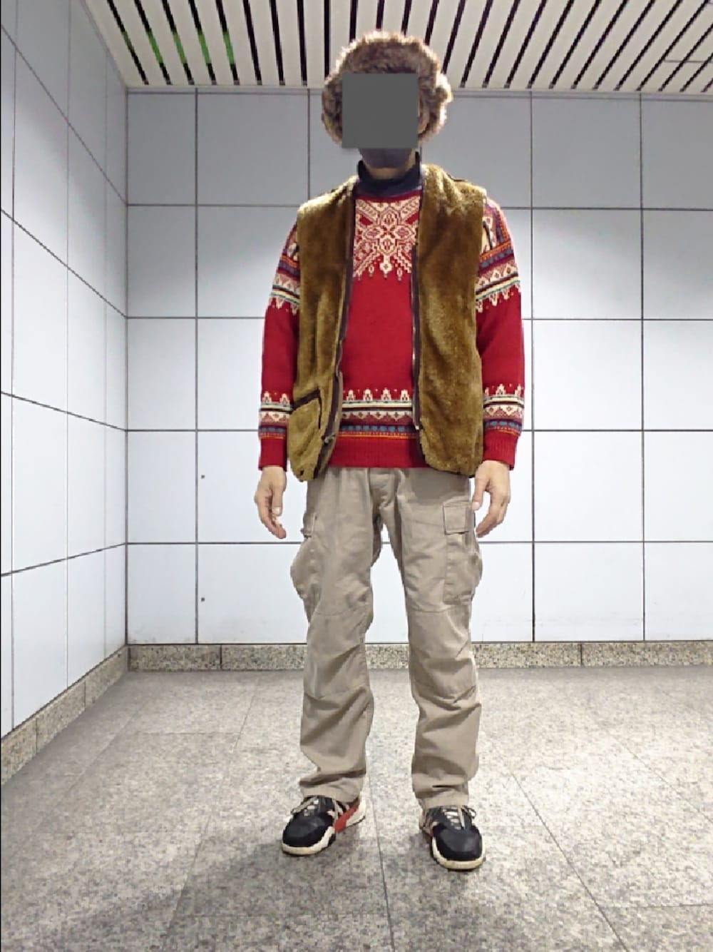 ブラウン系のベスト、グリーン系のカーゴパンツ、ブラック系のスニーカーを着用したメンズの春コーディネートの1枚目の写真