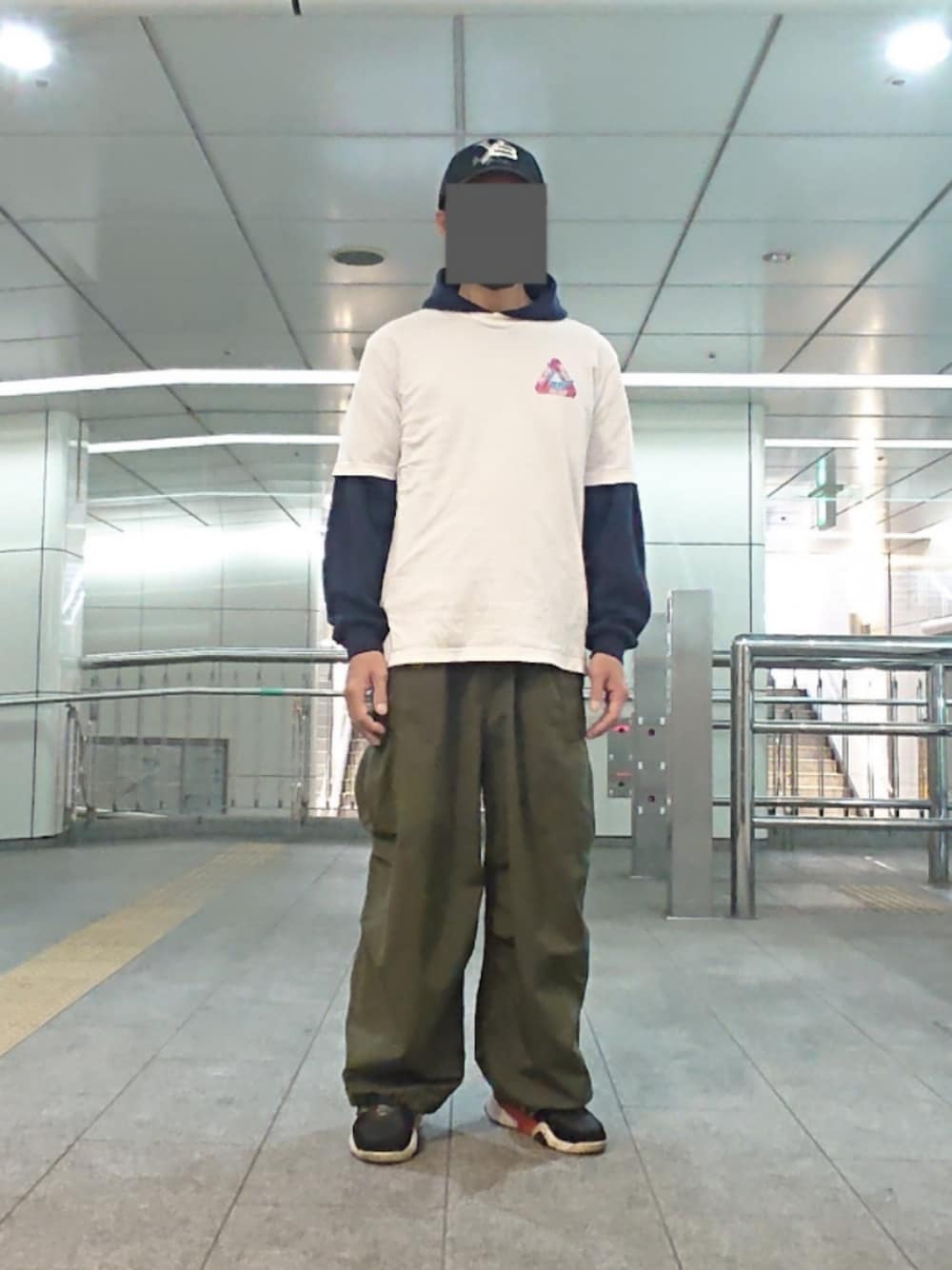 ホワイト系のTシャツ/カットソー、グリーン系のカーゴパンツ、ブラック系のスニーカーを着用したメンズの春コーディネートの1枚目の写真