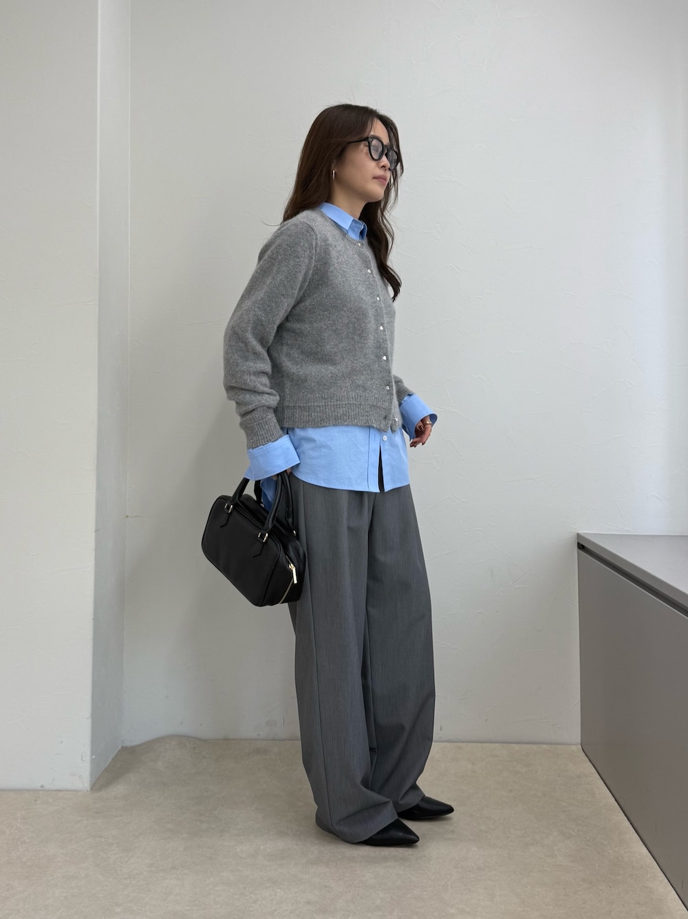 グレー系のカーディガン/ボレロ、ブルー系のシャツ/ブラウス、ブラック系のボストンバッグを着用したレディースの秋コーディネートの1枚目の写真