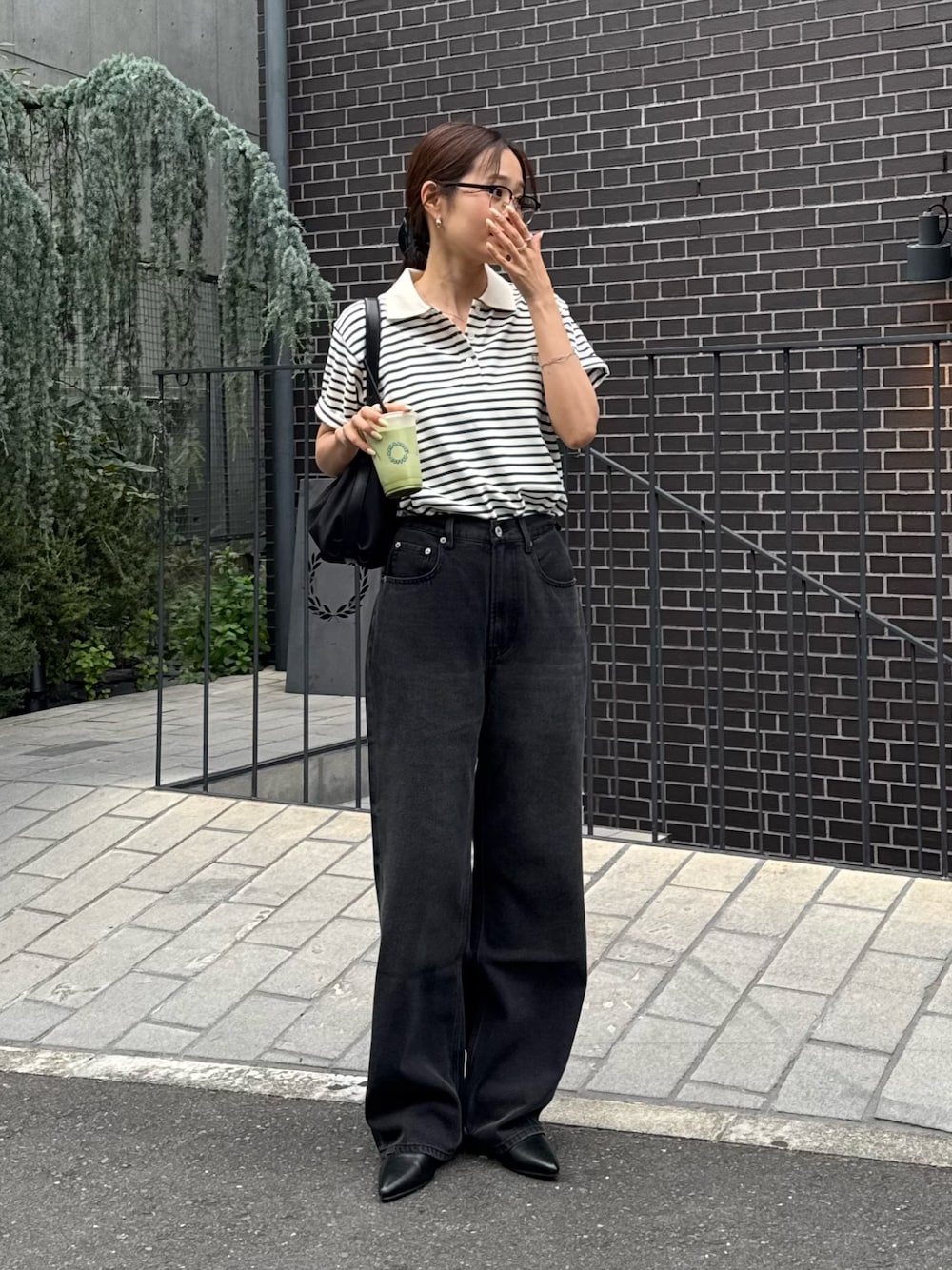 グリーン系のポロシャツ、ブラック系のデニムパンツ、ブラック系のパンプスを着用したレディースの夏コーディネートの1枚目の写真