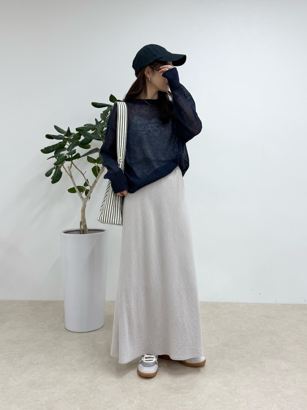 ブルー系のニット/セーター、ブラック系のショルダーバッグ、ベージュ系のスカートを着用したレディースの春コーディネートの1枚目の写真