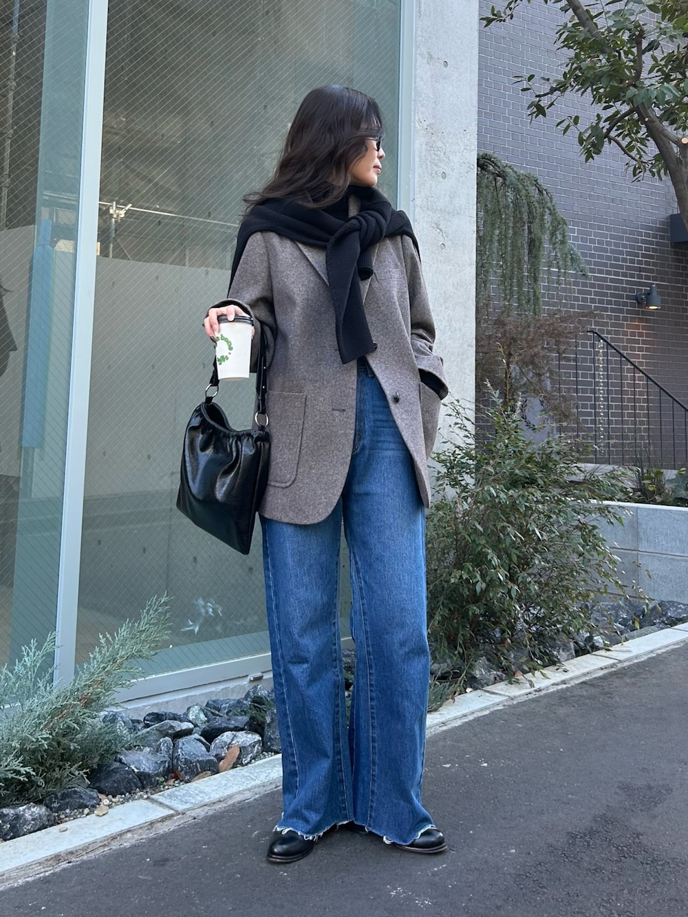 ブルー系のデニムパンツ、ブラウン系のテーラードジャケット、ブラック系のニット/セーターを着用したレディースの冬コーディネートの1枚目の写真