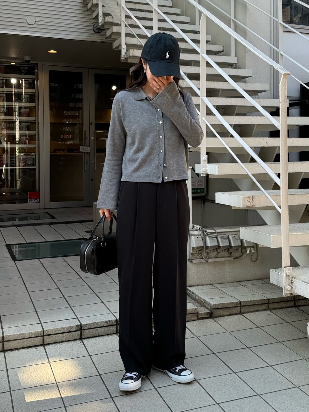 グレー系のカーディガン/ボレロ、ブラック系のスラックス、ブラック系のハンドバッグを着用したレディースの冬コーディネートの1枚目の写真