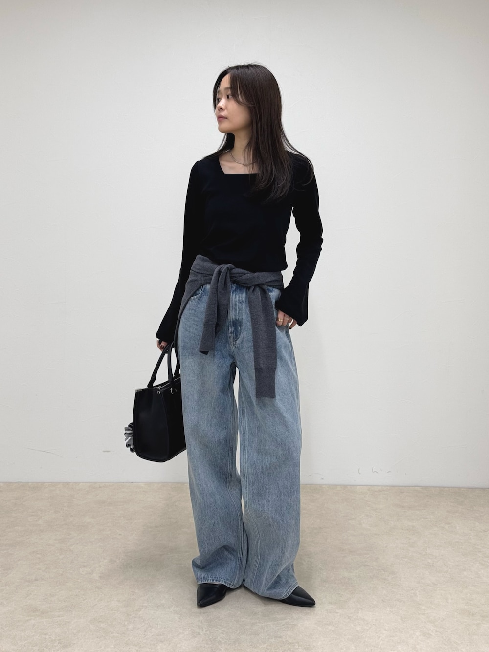 ブラック系のTシャツ/カットソー、ブルー系のデニムパンツ、ブラック系のボストンバッグを着用したレディースの秋コーディネートの1枚目の写真
