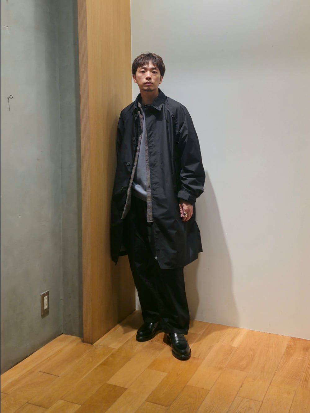 ブラック系のステンカラーコート、グレー系のシャツ/ブラウス、グレー系のTシャツ/カットソーを着用したメンズの秋コーディネートの1枚目の写真