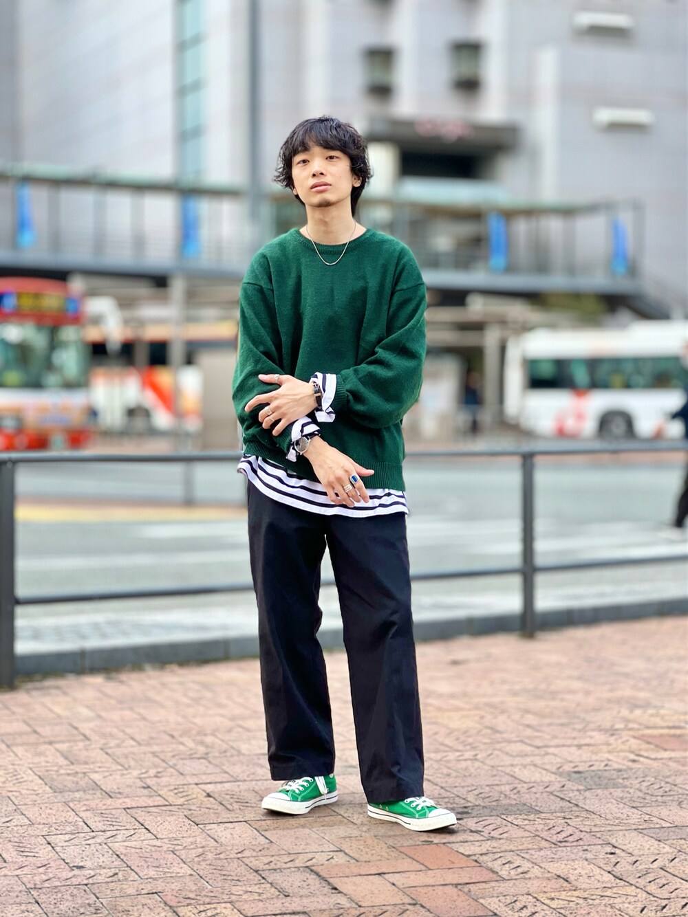 グリーン系のニット/セーター、ブラック系のTシャツ/カットソー、ブラック系のスラックスを着用したメンズの秋コーディネートの1枚目の写真