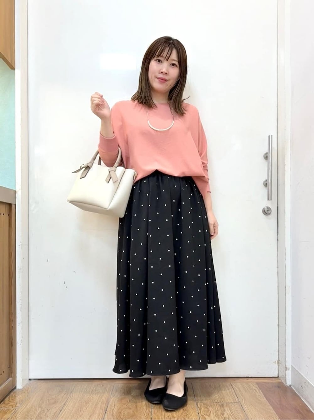ピンク系のシャツ/ブラウス、ブラック系のスカート、ブラック系のパンプスを着用したレディースの春コーディネートの1枚目の写真