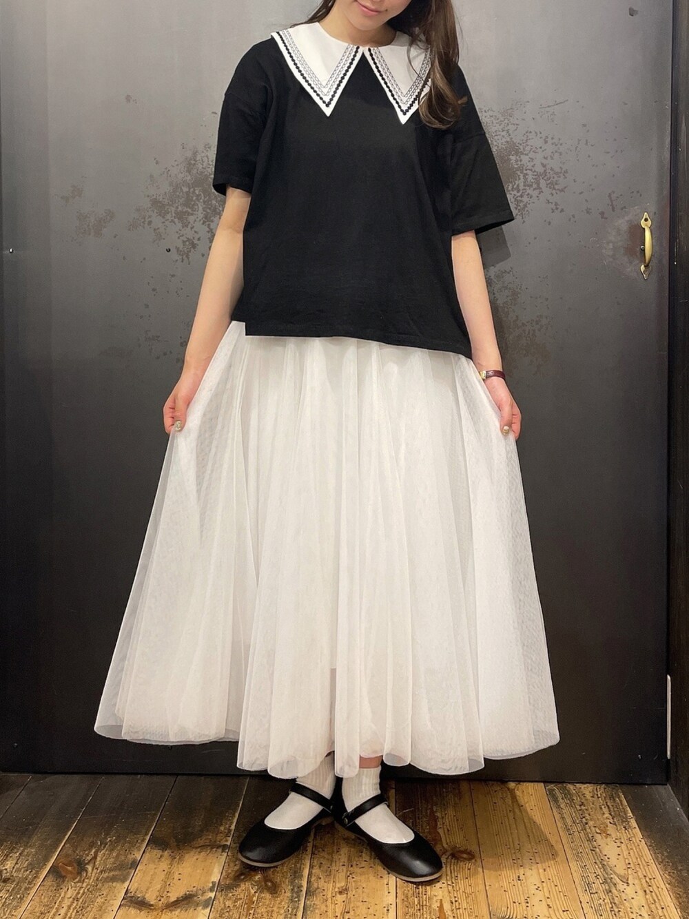 ホワイト系のスカート、ブラック系のTシャツ/カットソーを着用したレディースの夏コーディネートの1枚目の写真