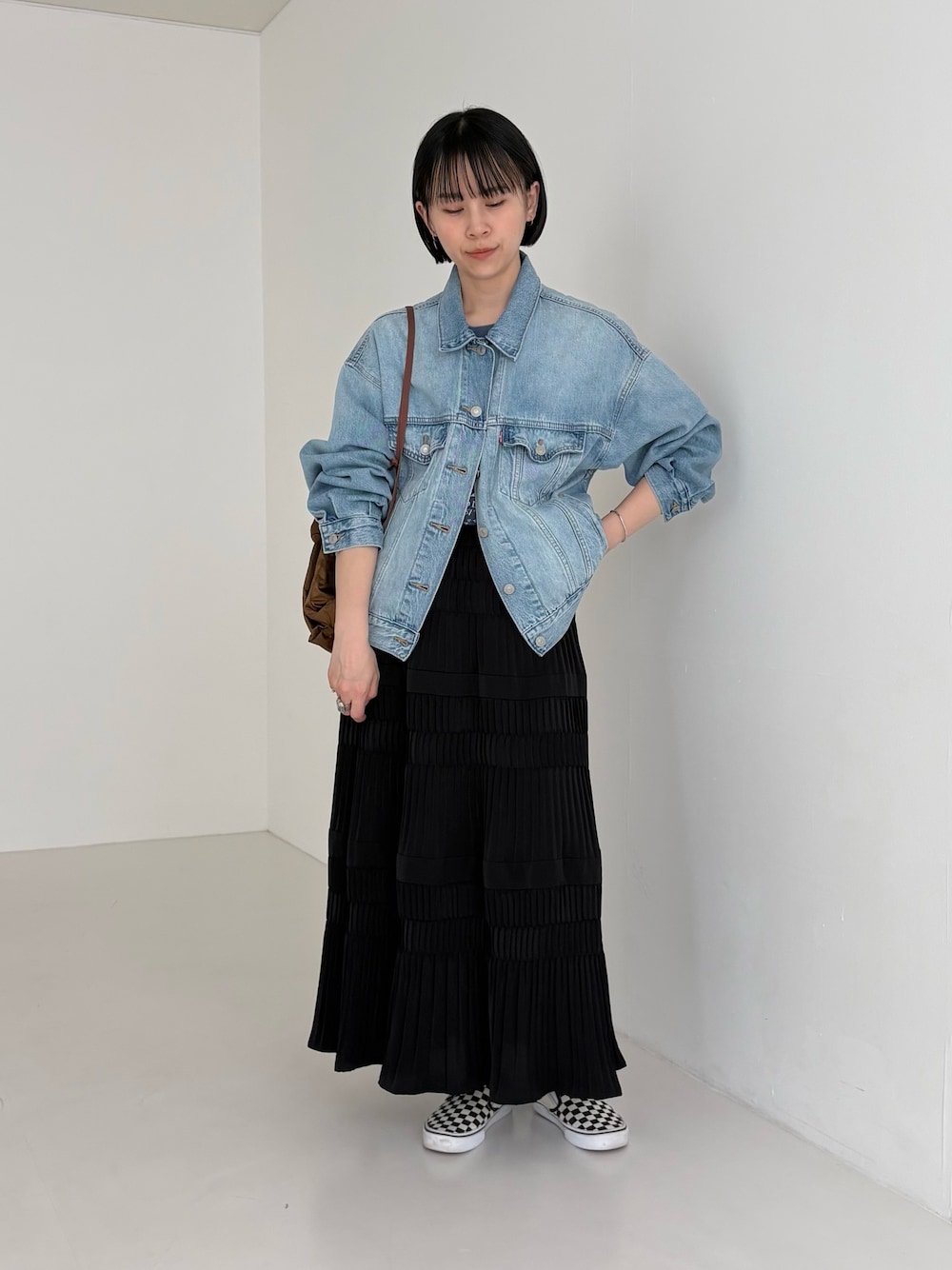 ブルー系のデニムジャケット、ブラウン系のバックパック/リュック、ブラック系のスカートを着用したレディースの春コーディネートの1枚目の写真