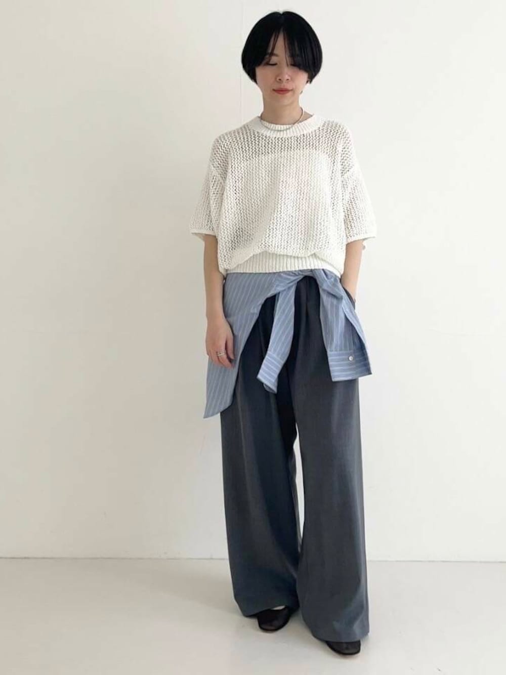 ブルー系のシャツ/ブラウス、グレー系のその他パンツ、ホワイト系のニット/セーターを着用したレディースの春コーディネートの1枚目の写真