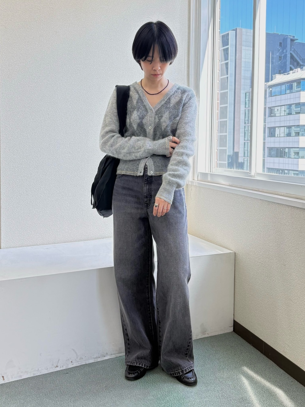 グレー系のニット/セーター、ブラック系のトートバッグ、ブラック系のデニムパンツを着用したレディースの秋コーディネートの1枚目の写真
