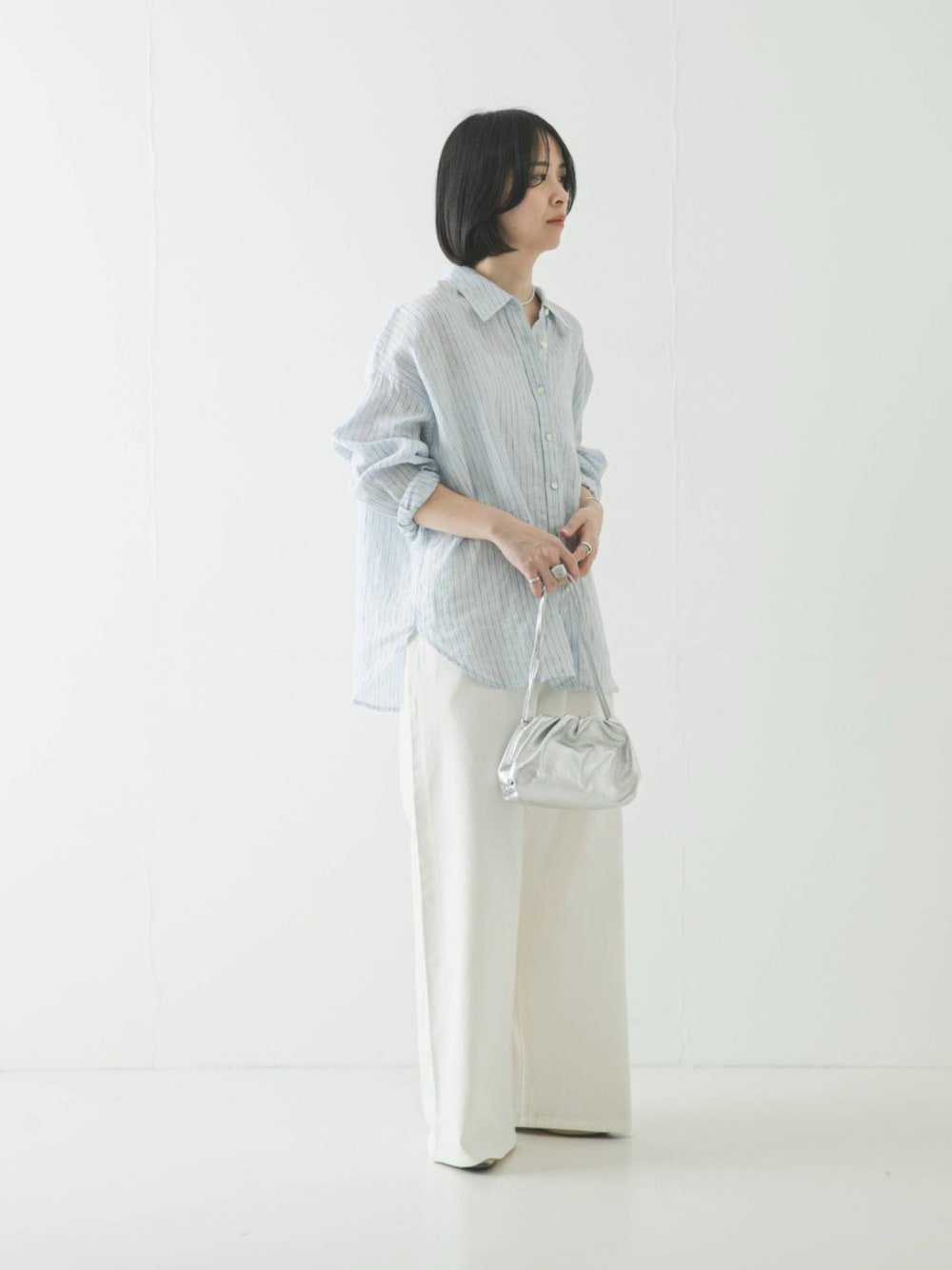 ブルー系のシャツ/ブラウス、シルバー系のショルダーバッグ、ホワイト系のデニムパンツを着用したレディースの春コーディネートの1枚目の写真