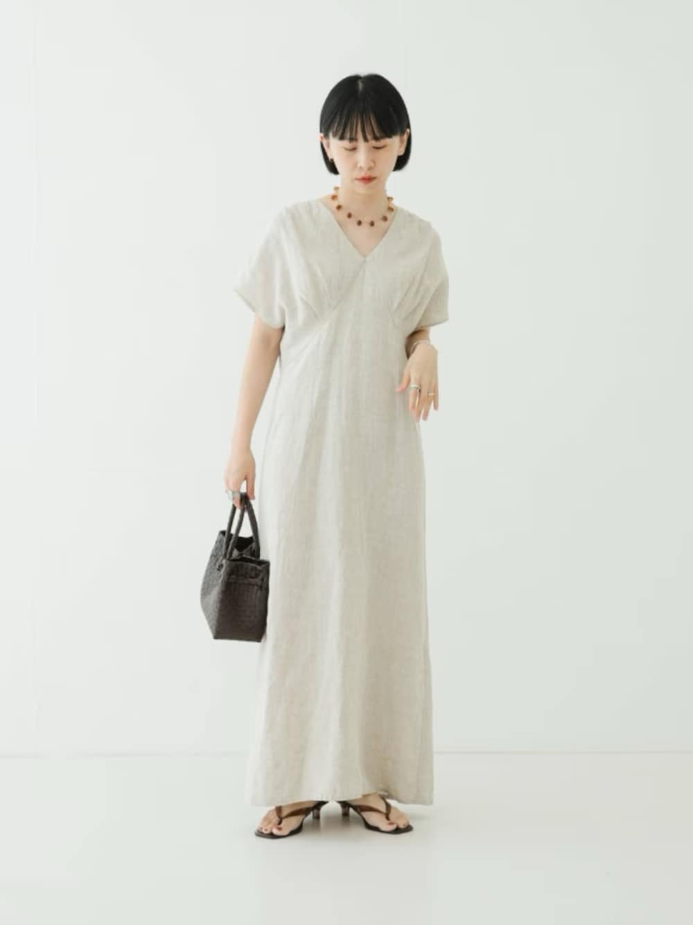 ベージュ系のワンピース、ブラウン系のトートバッグ、ブラウン系のサンダルを着用したレディースの夏コーディネートの1枚目の写真