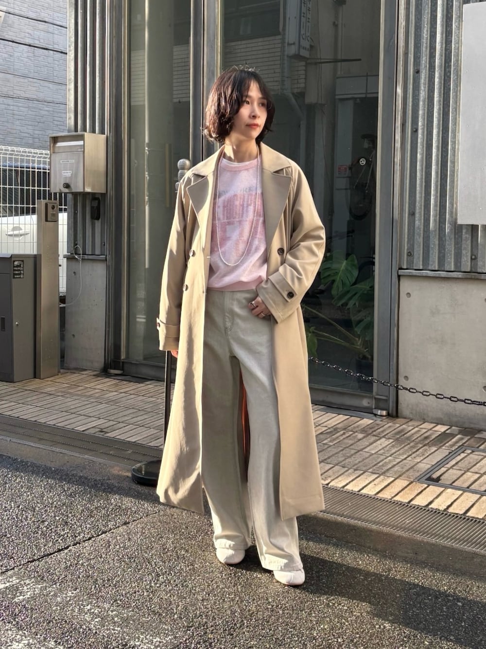 グレー系のデニムパンツ、ベージュ系のトレンチコート、ピンク系のニット/セーターを着用したレディースの冬コーディネートの1枚目の写真