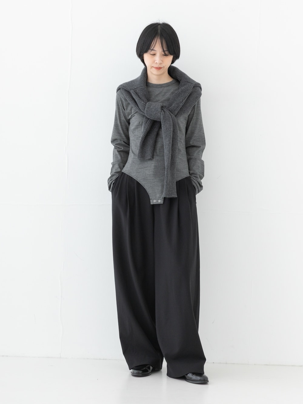 グレー系のニット/セーター、ブラック系のその他パンツ、ブラック系のTシャツ/カットソーを着用したレディースの秋コーディネートの1枚目の写真