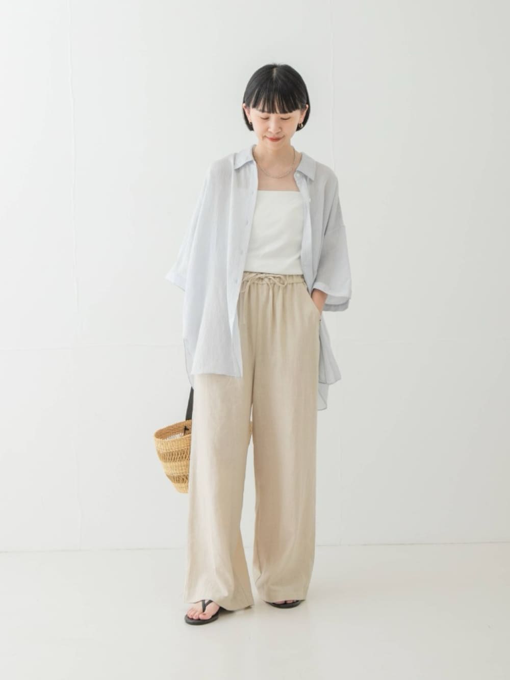 ブルー系のシャツ/ブラウス、ベージュ系のその他パンツ、ベージュ系のかごバッグを着用したレディースの夏コーディネートの1枚目の写真