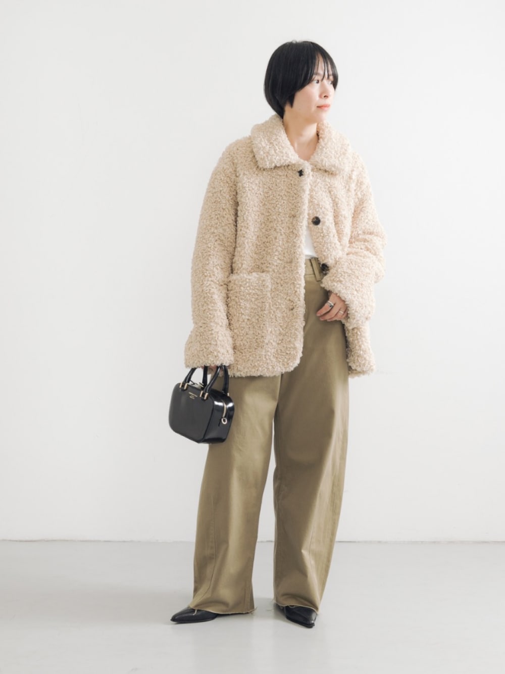 ホワイト系のその他アウター、ブラック系のブーツ、ブラック系のショルダーバッグを着用したレディースの秋コーディネートの1枚目の写真