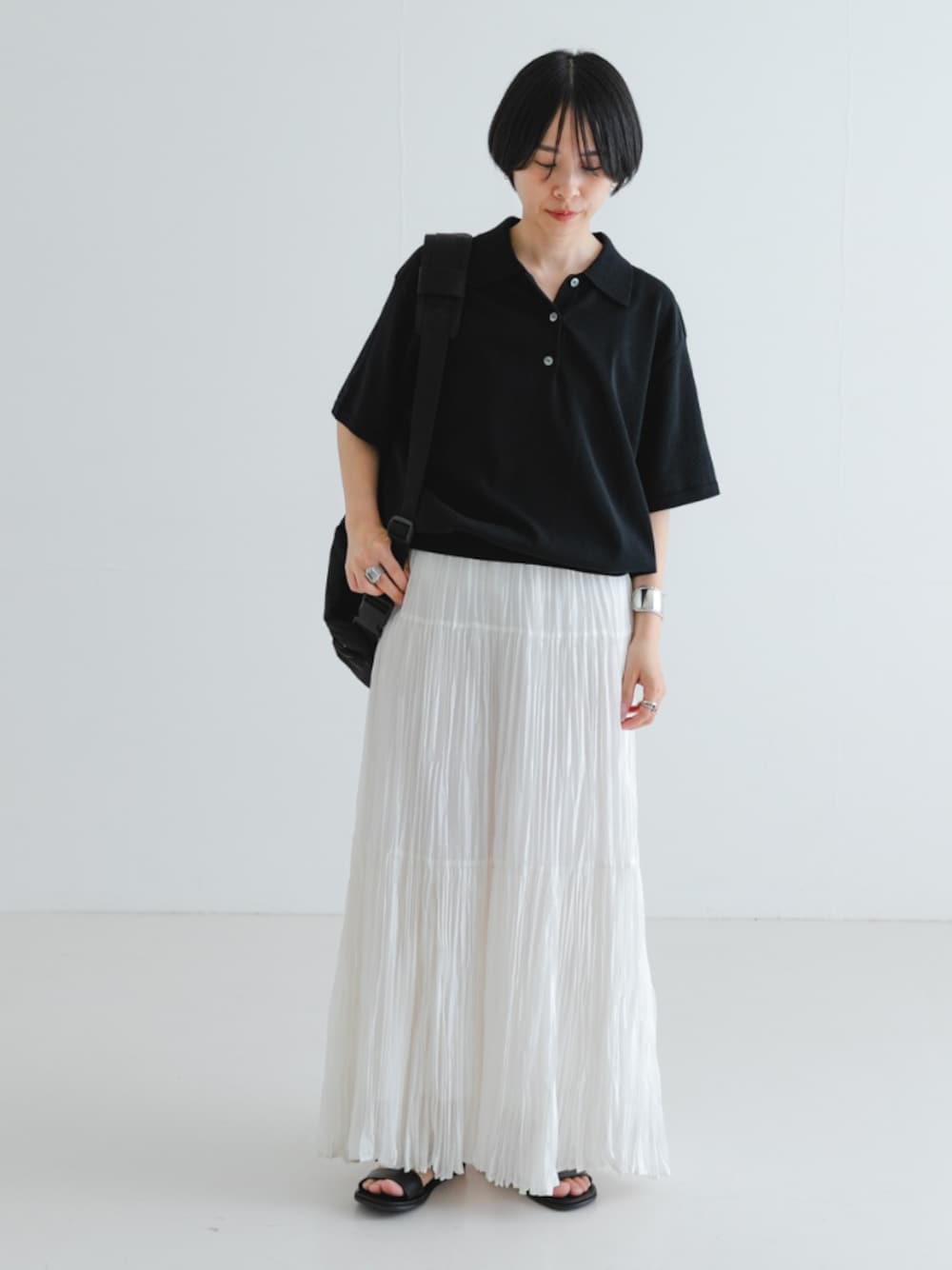 ブラック系のサンダル、ブラック系のバックパック/リュック、ホワイト系のスカートを着用したレディースの夏コーディネートの1枚目の写真