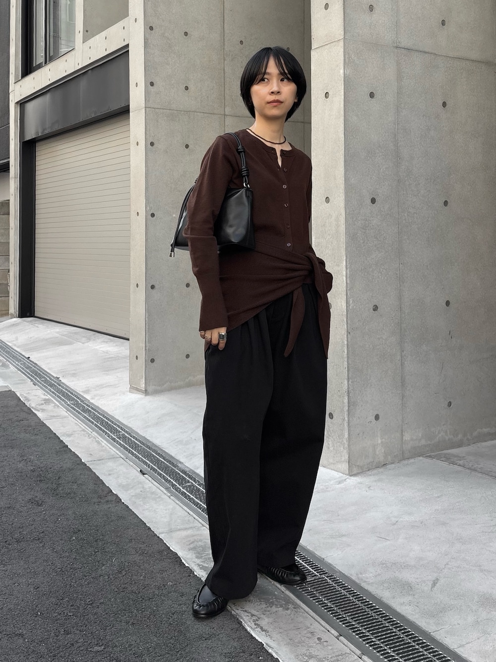 ブラック系のハンドバッグ、ブラウン系のカーディガン/ボレロ、ブラック系のその他パンツを着用したレディースの秋コーディネートの1枚目の写真