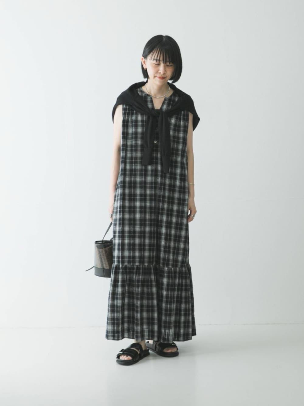 ブラック系のカーディガン/ボレロ、ブラック系のワンピース、ブラック系のサンダルを着用したレディースの春コーディネートの1枚目の写真