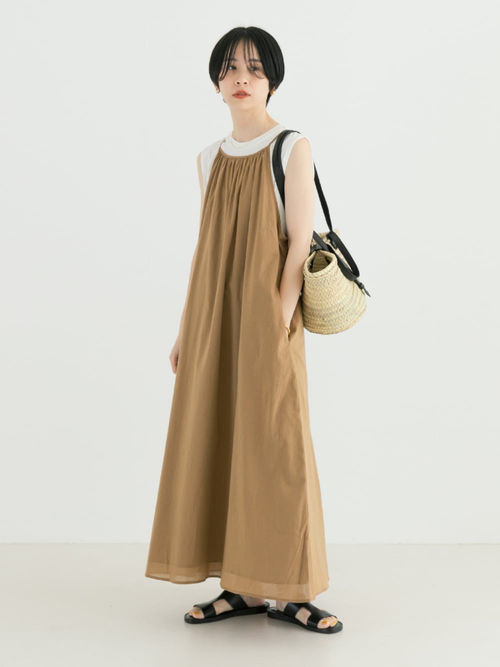 ベージュ系のワンピース、ブラック系のかごバッグを着用したレディースの春コーディネートの1枚目の写真