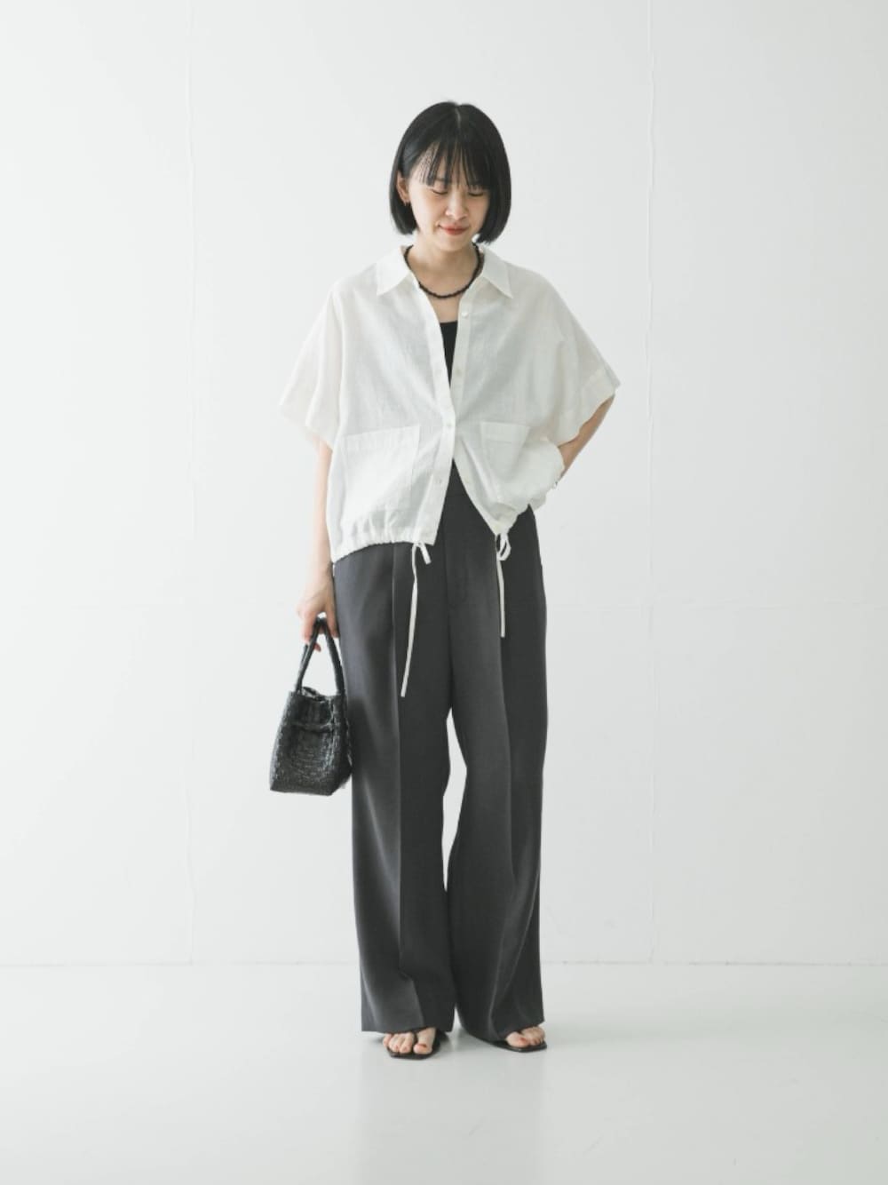 グレー系のその他パンツ、ブラック系のサンダル、ホワイト系のシャツ/ブラウスを着用したレディースの春コーディネートの1枚目の写真