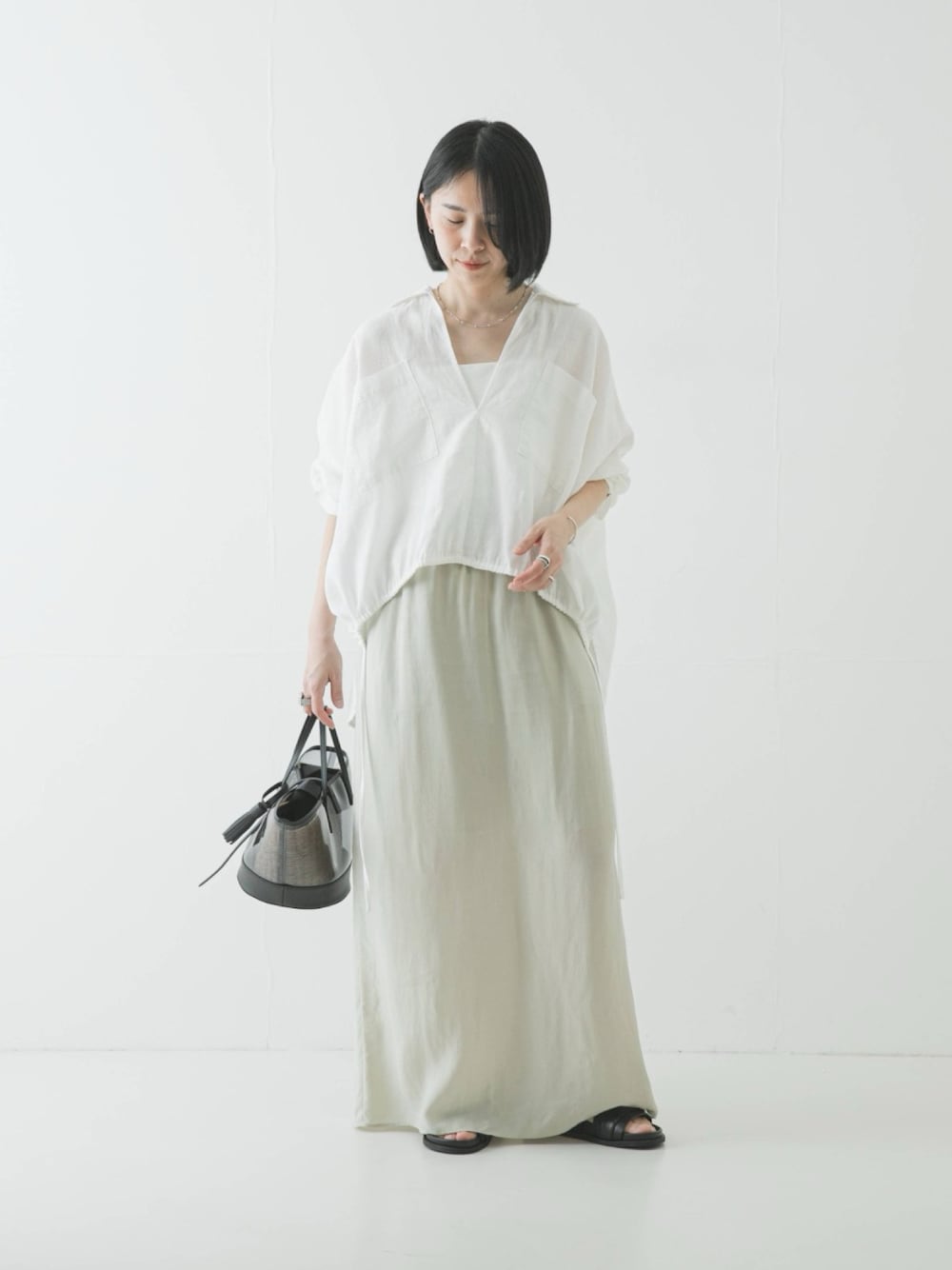 ホワイト系のシャツ/ブラウス、ブラック系のかごバッグ、ベージュ系のスカートを着用したレディースの春コーディネートの1枚目の写真