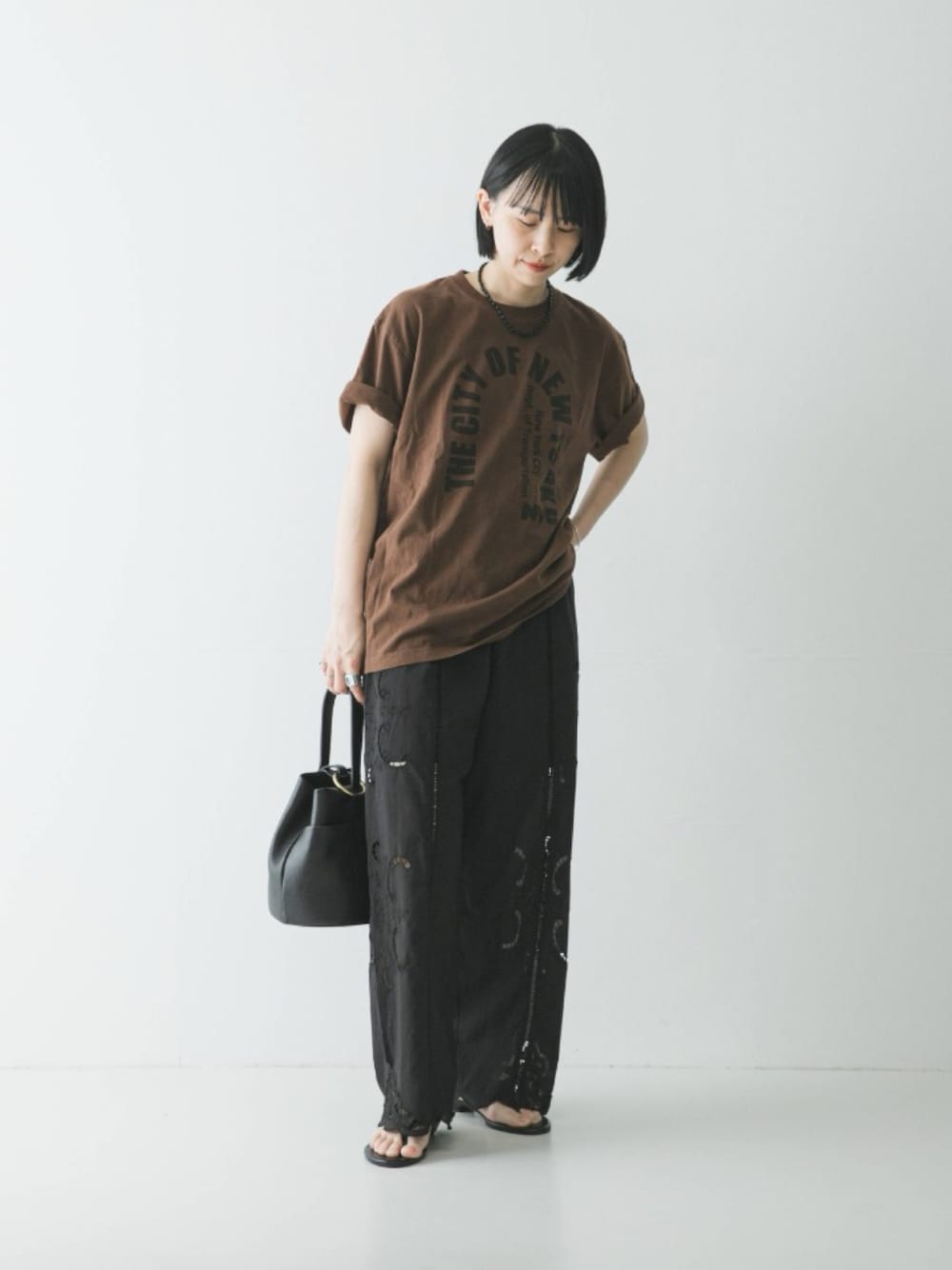 ブラウン系のTシャツ/カットソー、ブラック系のその他パンツ、ブラック系のハンドバッグを着用したレディースの春コーディネートの1枚目の写真