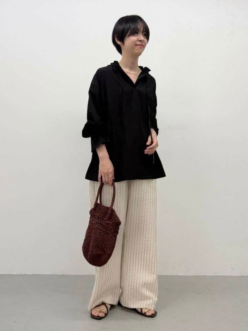 ブラック系のシャツ/ブラウス、ブラウン系のショルダーバッグ、ベージュ系のその他パンツを着用したレディースの春コーディネートの1枚目の写真