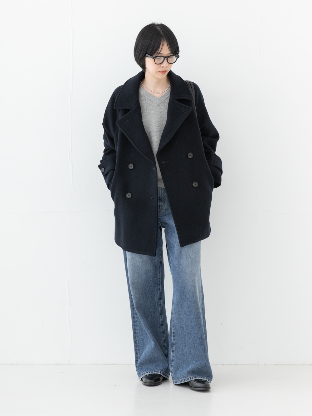 ブルー系のデニムパンツ、ブルー系のピーコート、グリーン系のトートバッグを着用したレディースの秋コーディネートの1枚目の写真