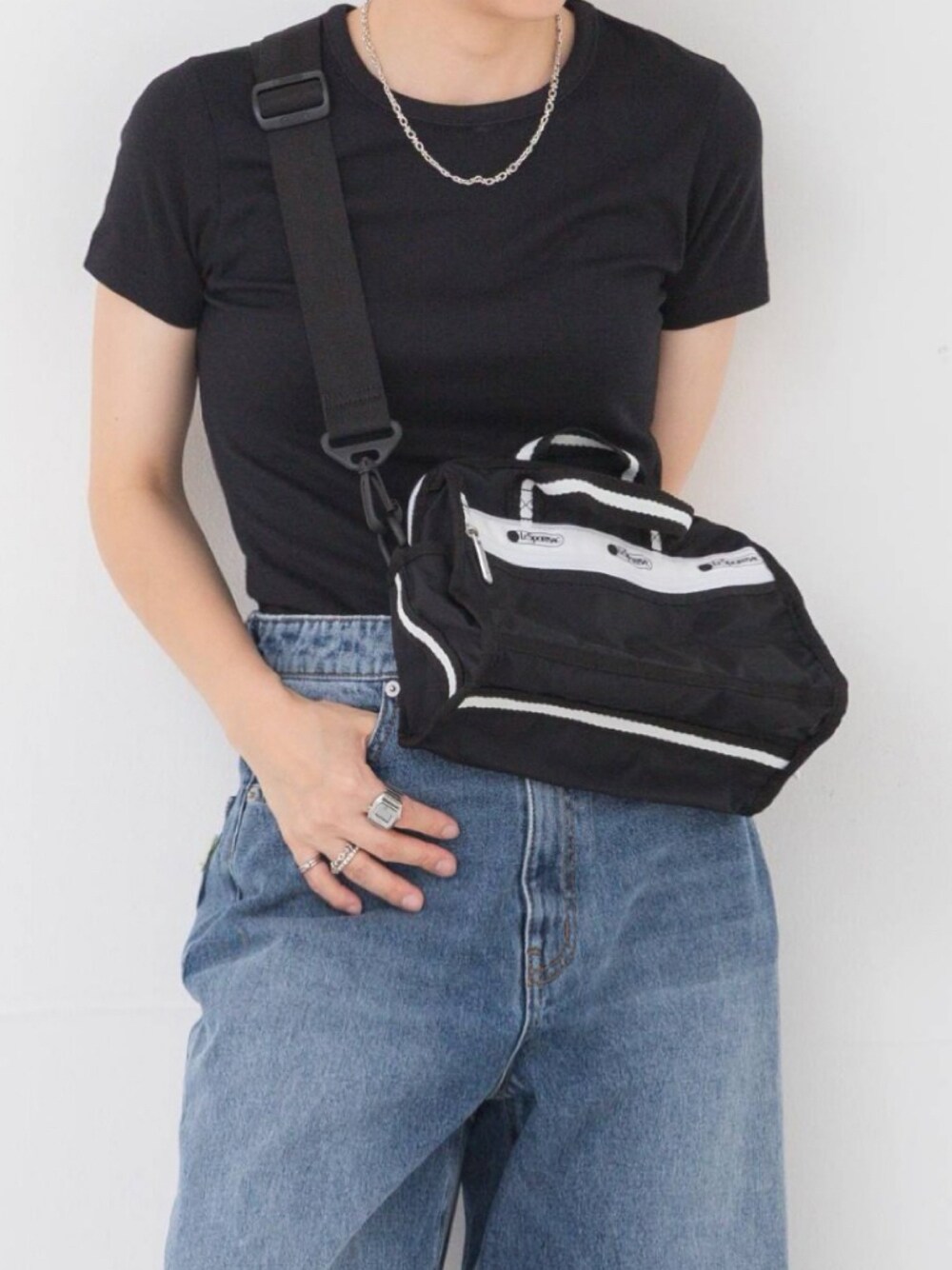 ブラック系のTシャツ/カットソー、ブラック系のショルダーバッグ、ブルー系のデニムパンツを着用したレディースの夏コーディネートの1枚目の写真