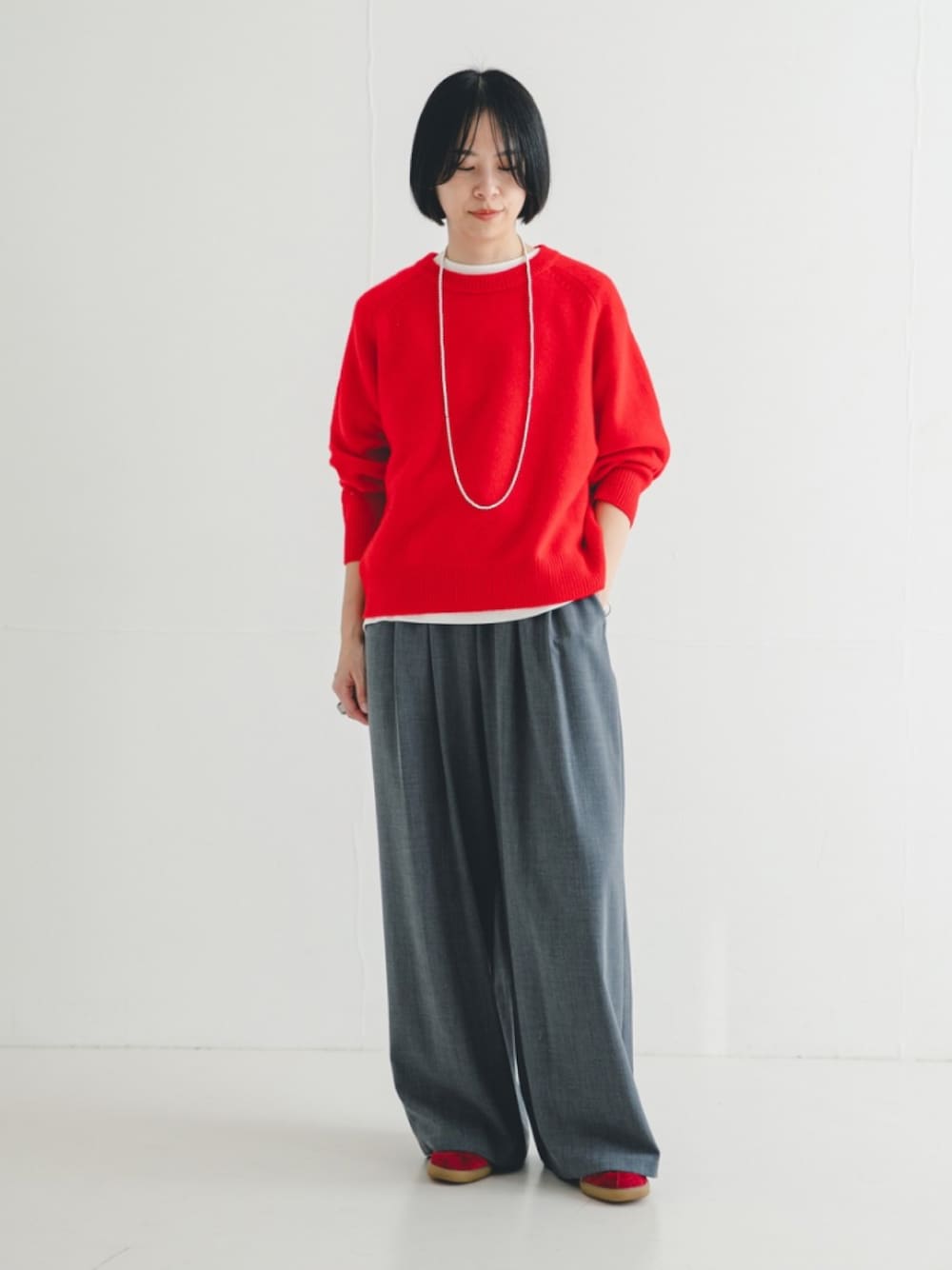 レッド系のニット/セーター、グレー系のその他パンツを着用したレディースの冬コーディネートの1枚目の写真