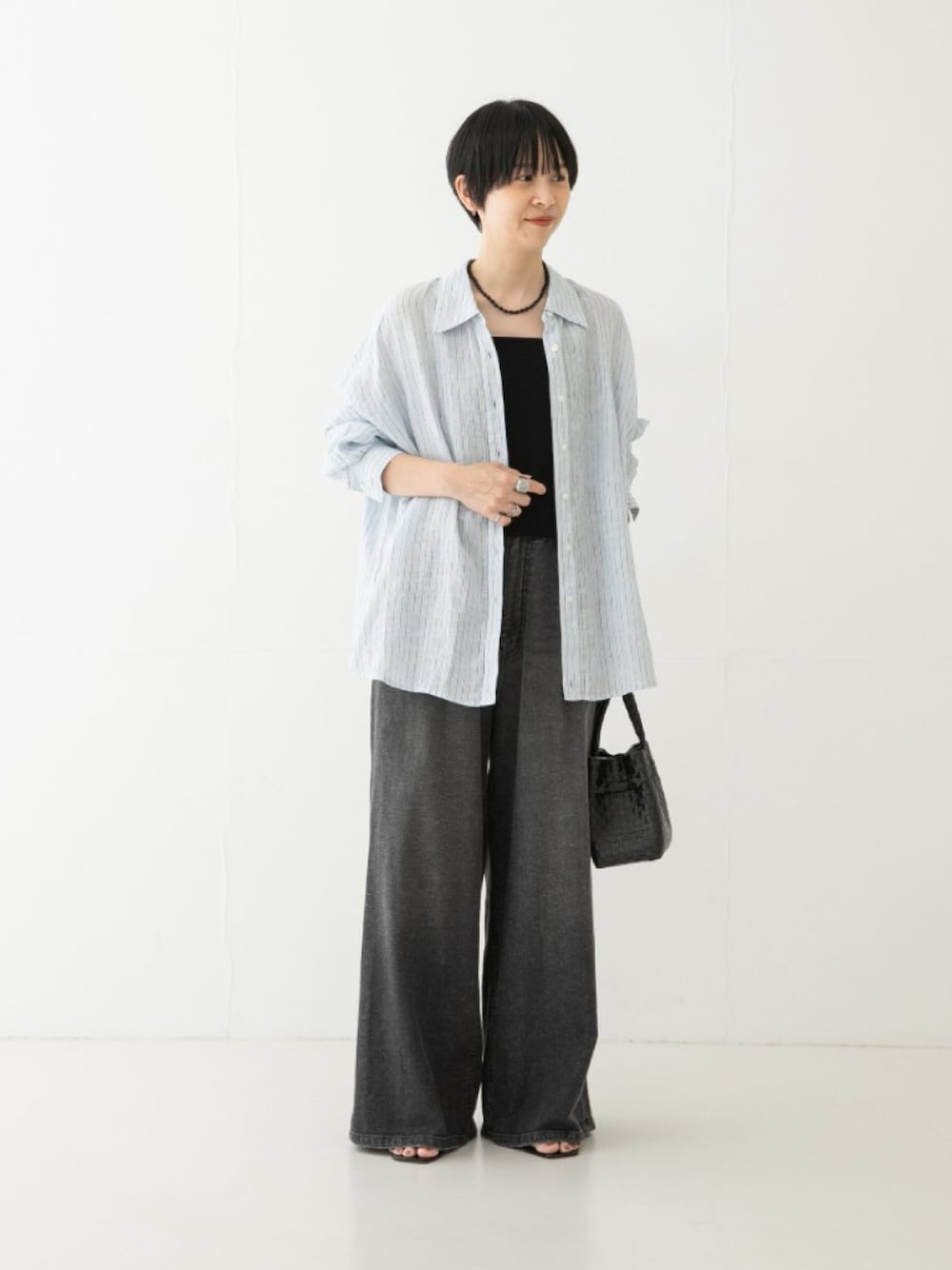 ブラック系のデニムパンツ、ブラック系のトートバッグ、ブルー系のシャツ/ブラウスを着用したレディースの夏コーディネートの1枚目の写真