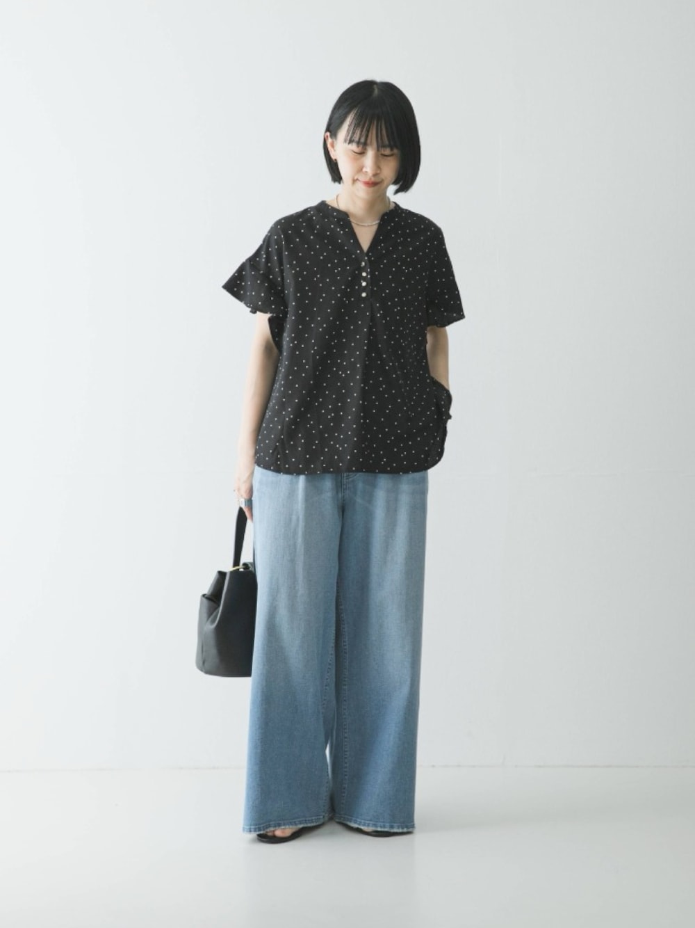 ブラック系のシャツ/ブラウス、ブルー系のデニムパンツ、ブラック系のハンドバッグを着用したレディースの春コーディネートの1枚目の写真