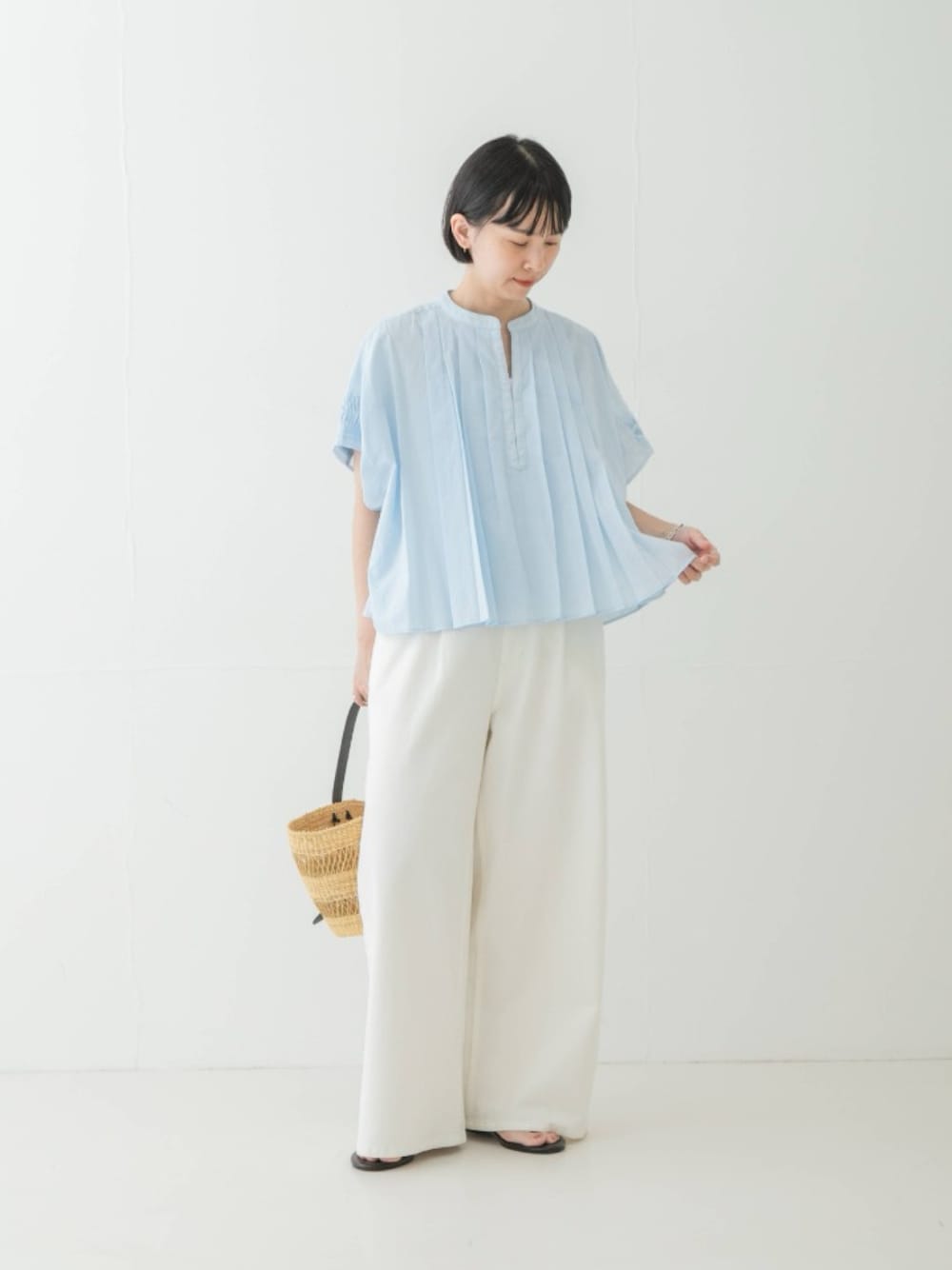 ブルー系のシャツ/ブラウス、ブラック系のサンダル、ベージュ系のかごバッグを着用したレディースの夏コーディネートの1枚目の写真