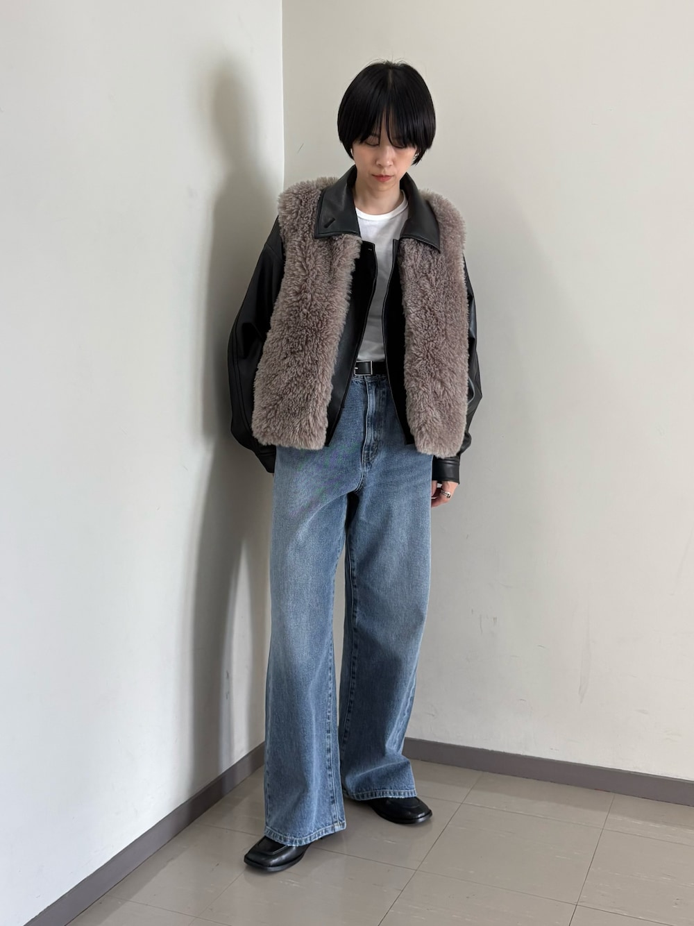 グレー系のダウンベスト、ブラック系のブルゾン、ブルー系のデニムパンツを着用したレディースの秋コーディネートの1枚目の写真