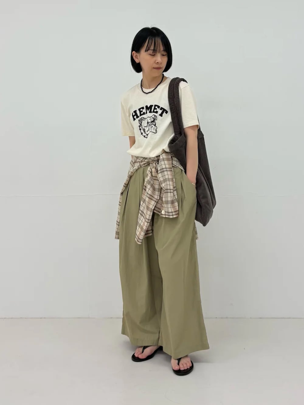 ベージュ系のTシャツ/カットソー、ベージュ系のその他パンツ、ブラウン系のトートバッグを着用したレディースの春コーディネートの1枚目の写真