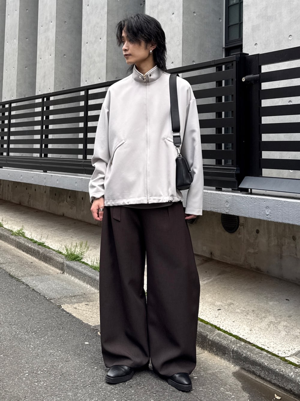 グレー系のスラックス、グレー系のブルゾン、ブラック系のショルダーバッグを着用したメンズの春コーディネートの1枚目の写真