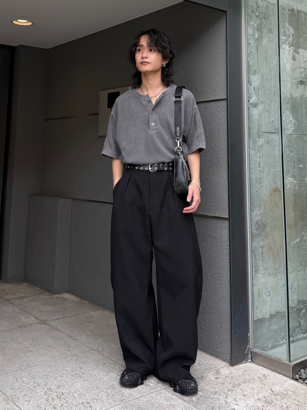 グレー系のTシャツ/カットソー、ブラック系のショルダーバッグ、ブラック系のスラックスを着用したメンズの春コーディネートの1枚目の写真