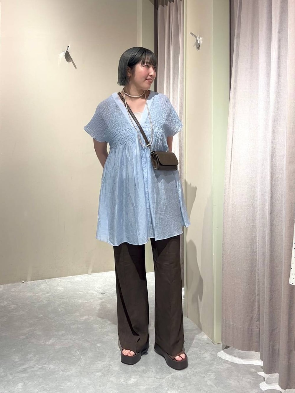 シルバー系のタンクトップ、ブルー系のシャツ/ブラウス、ブラウン系のスラックスを着用したレディースの春コーディネートの1枚目の写真