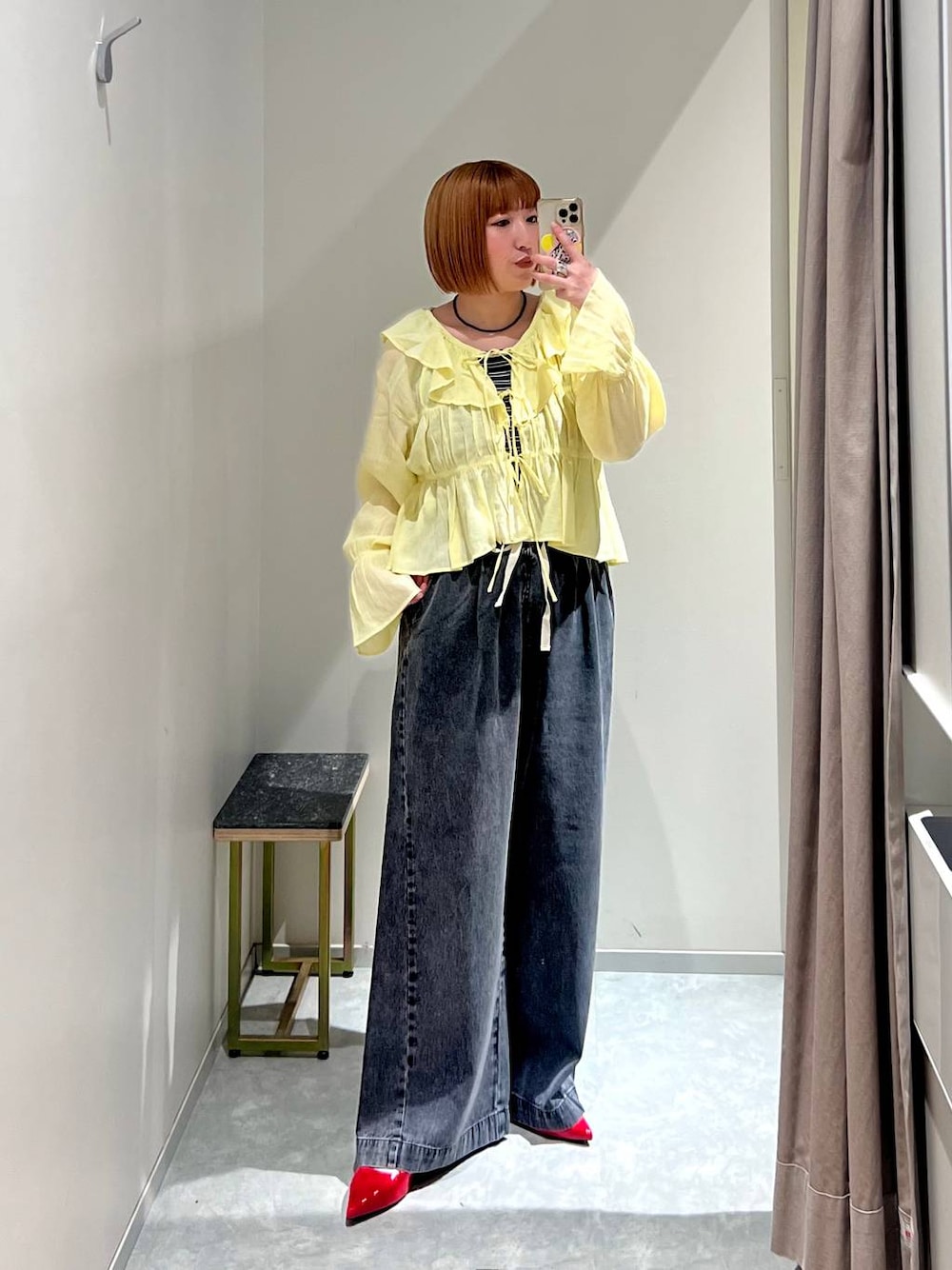 レッド系のパンプス、ブラック系のデニムパンツ、ブラウン系のタンクトップを着用したレディースの春コーディネートの1枚目の写真